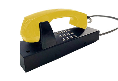 Telefone com a base preta, números para discagem prateados e parte de cima amarela, com o cabo prateado de metal.